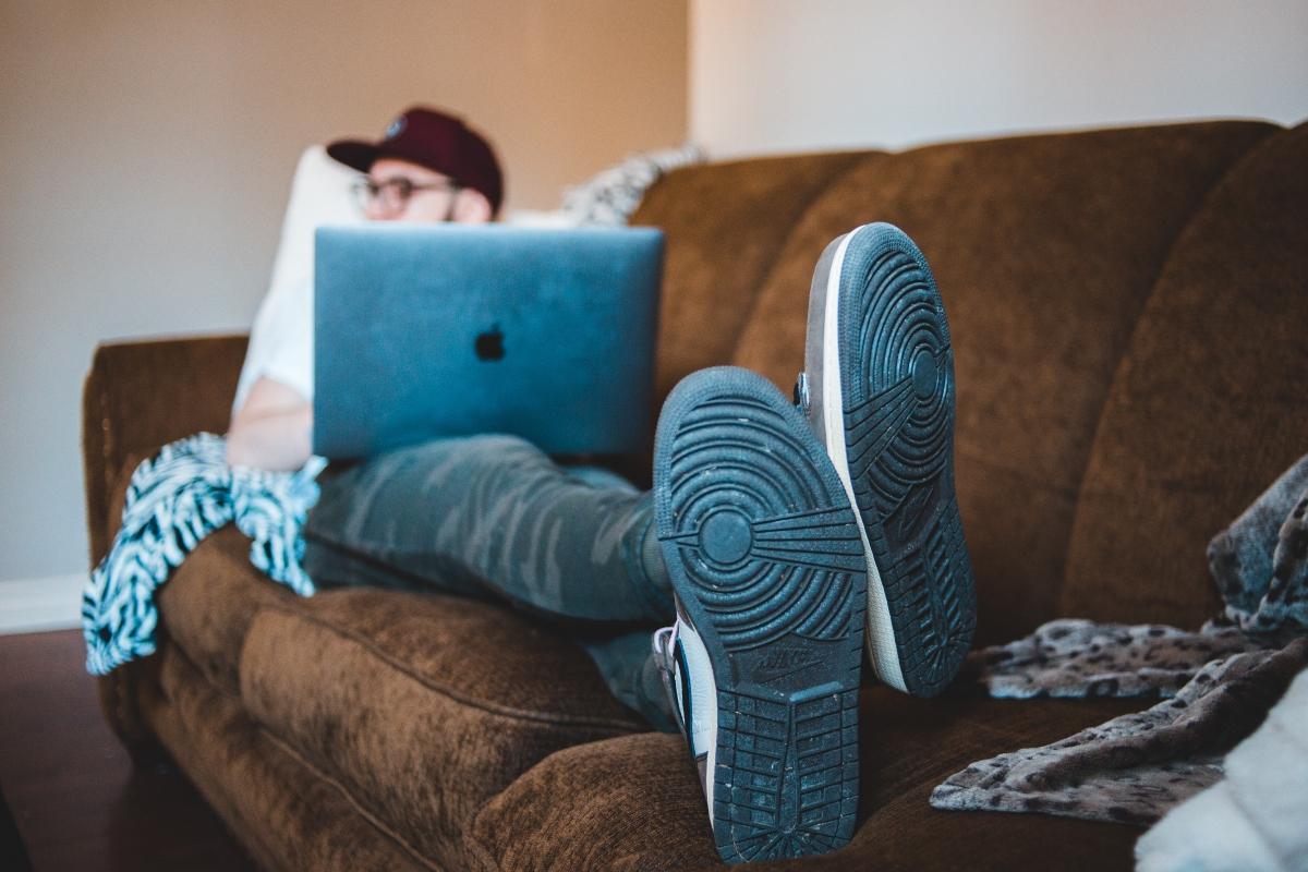 A man sitting on a couch with a laptop and watching tv