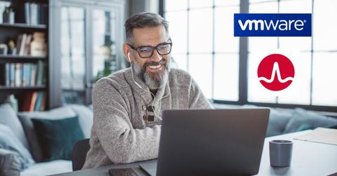 A man looking on a laptop and VMware and Broadcom logos