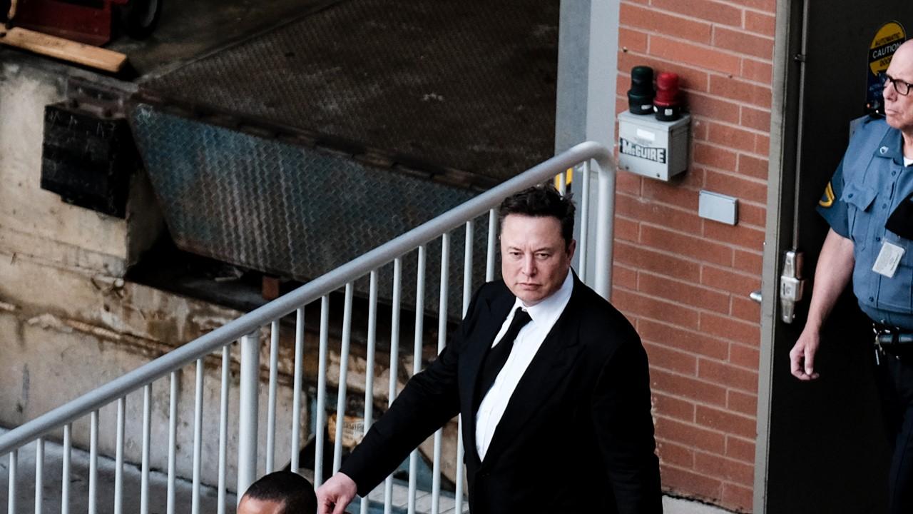 Elon Musk in suit walking