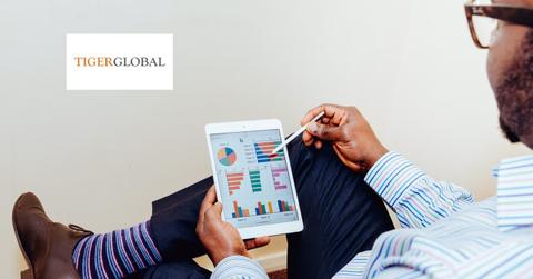 An investor looking at data and the Tiger Global Management logo