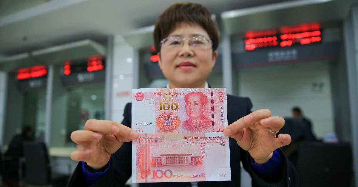 Chinese bank employee shows a yuan note