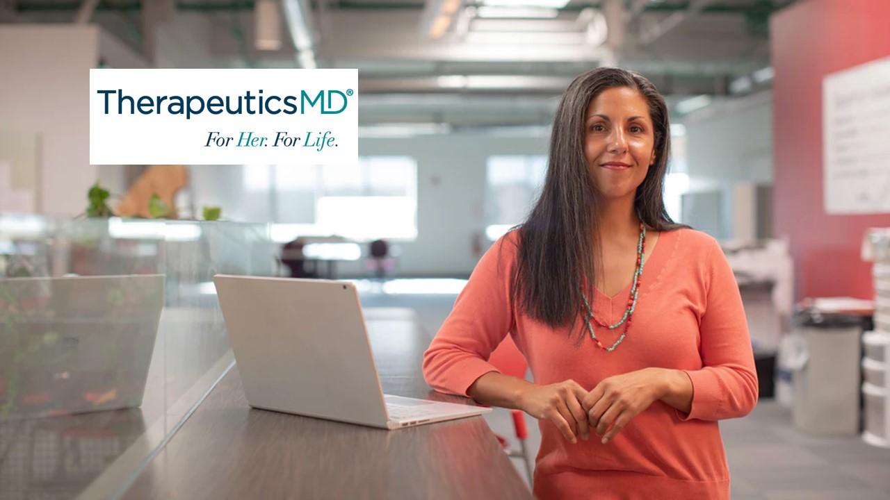 Woman standing near a laptop and TherapeuticsMD logo