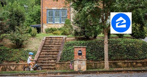 Child riding a bike in front of a home and Zillow logo