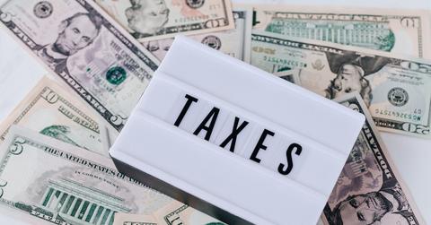 A white board displaying "taxes" on a pile of cash