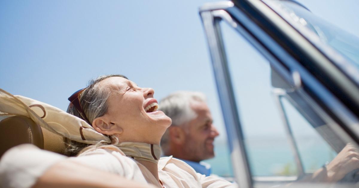 An older couple riding in a convertible car.