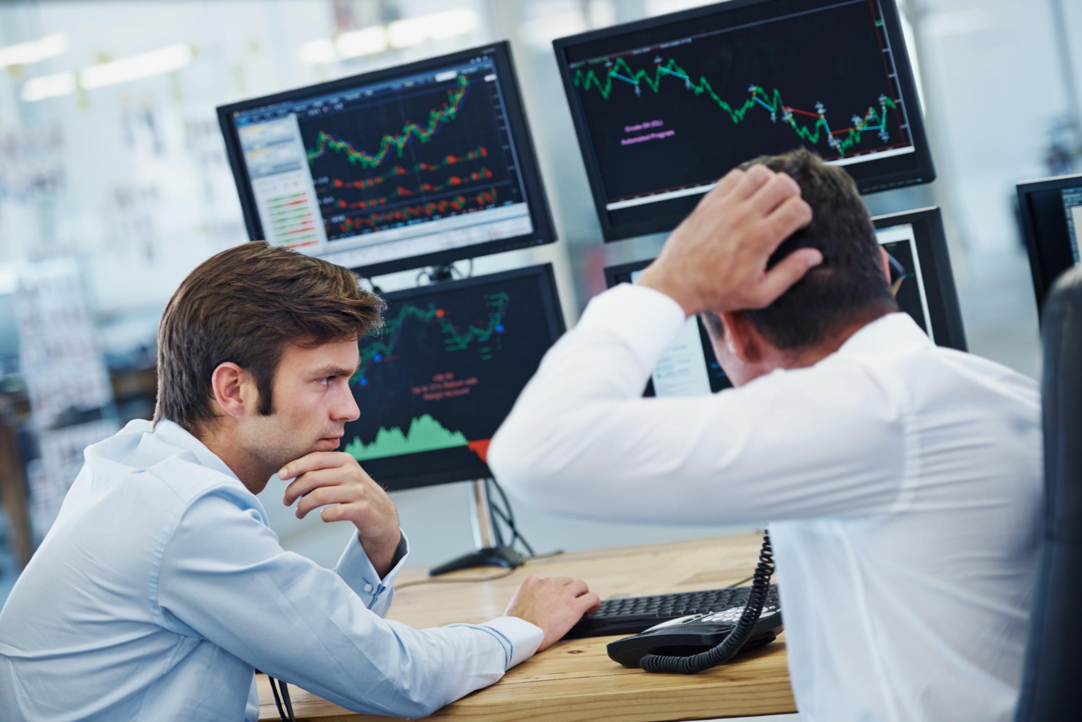 Confused investors looking at computer screens