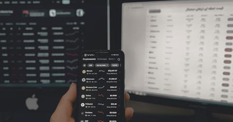 Person holding smartphone displaying crypto prices