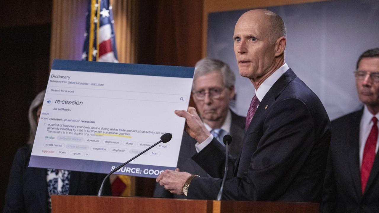 Senator Rick Scott holding up a sign 