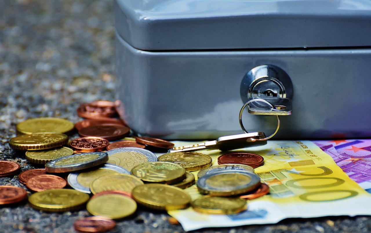 Coins and cash beside a lockbox