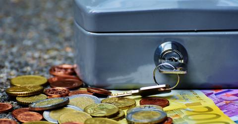 Coins and cash beside a lockbox