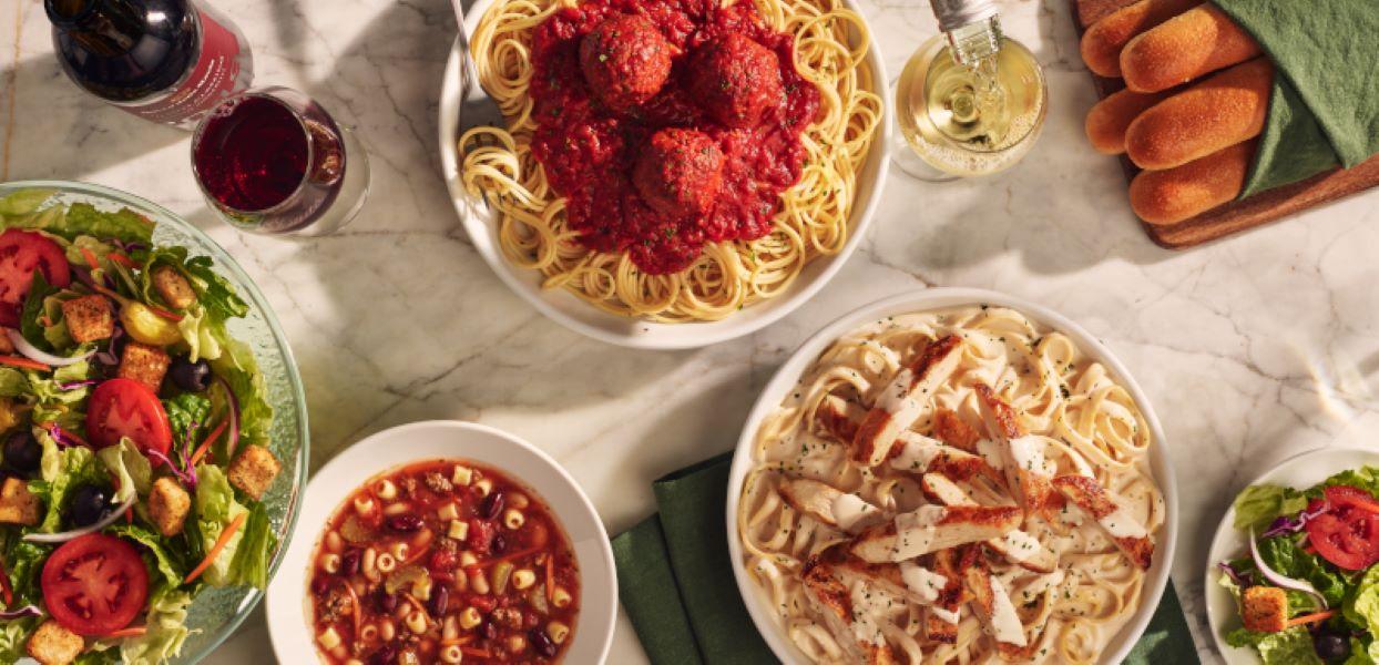 Olive Garden table set with pasta, wine, salad and breadsticks