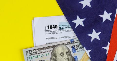 Form 1040, a $100 bill, and an American flag