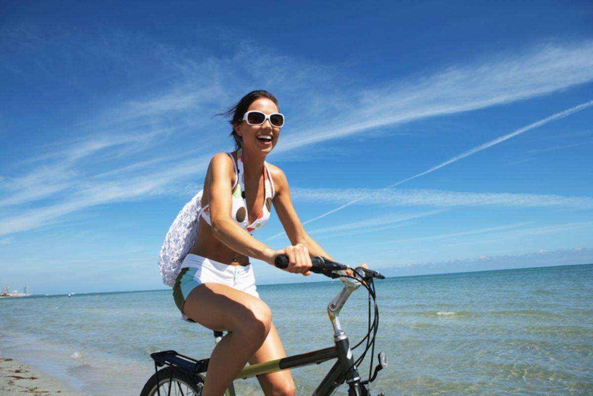 Young woman smiling and riding a bicycle on the beach