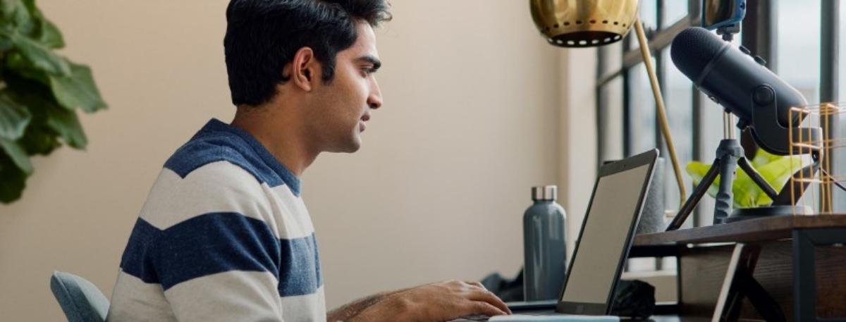 A man in a striped shirt using a laptop