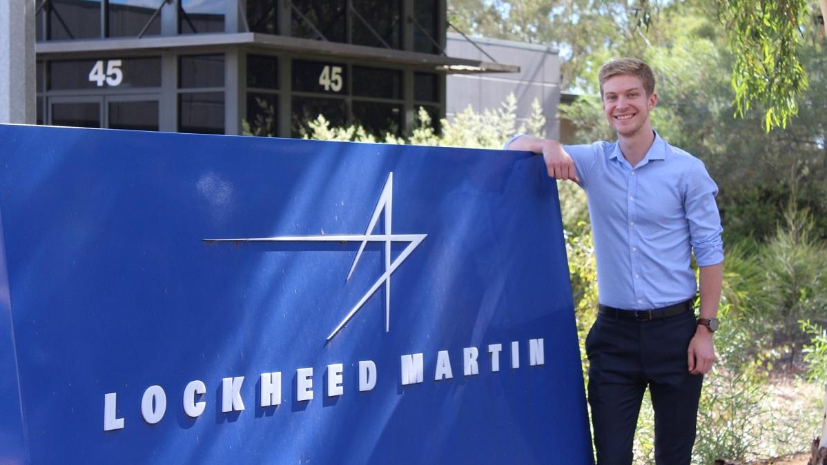 Man standing next to a Lockheed Martin sign