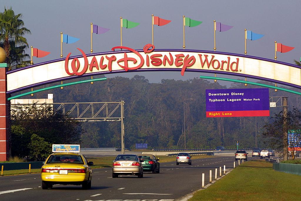 Cars drive into Walt Disney World through the entrance and under the arch