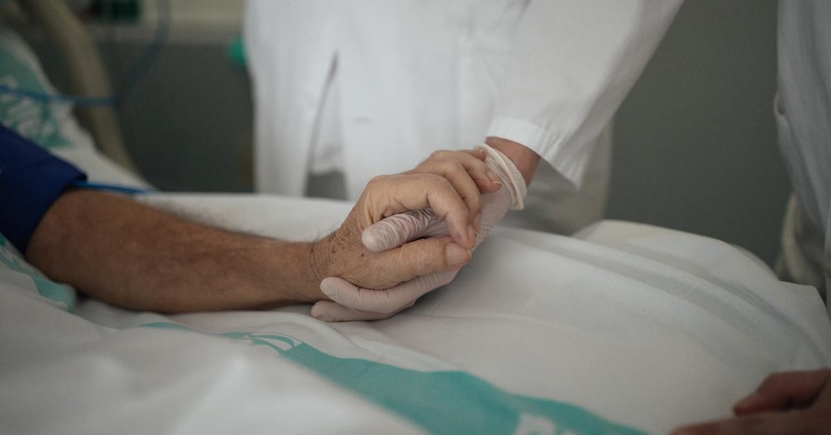 Elderly person holding the hand of a healthcare worker