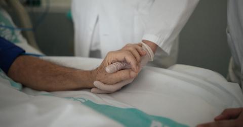 Elderly person holding the hand of a healthcare worker