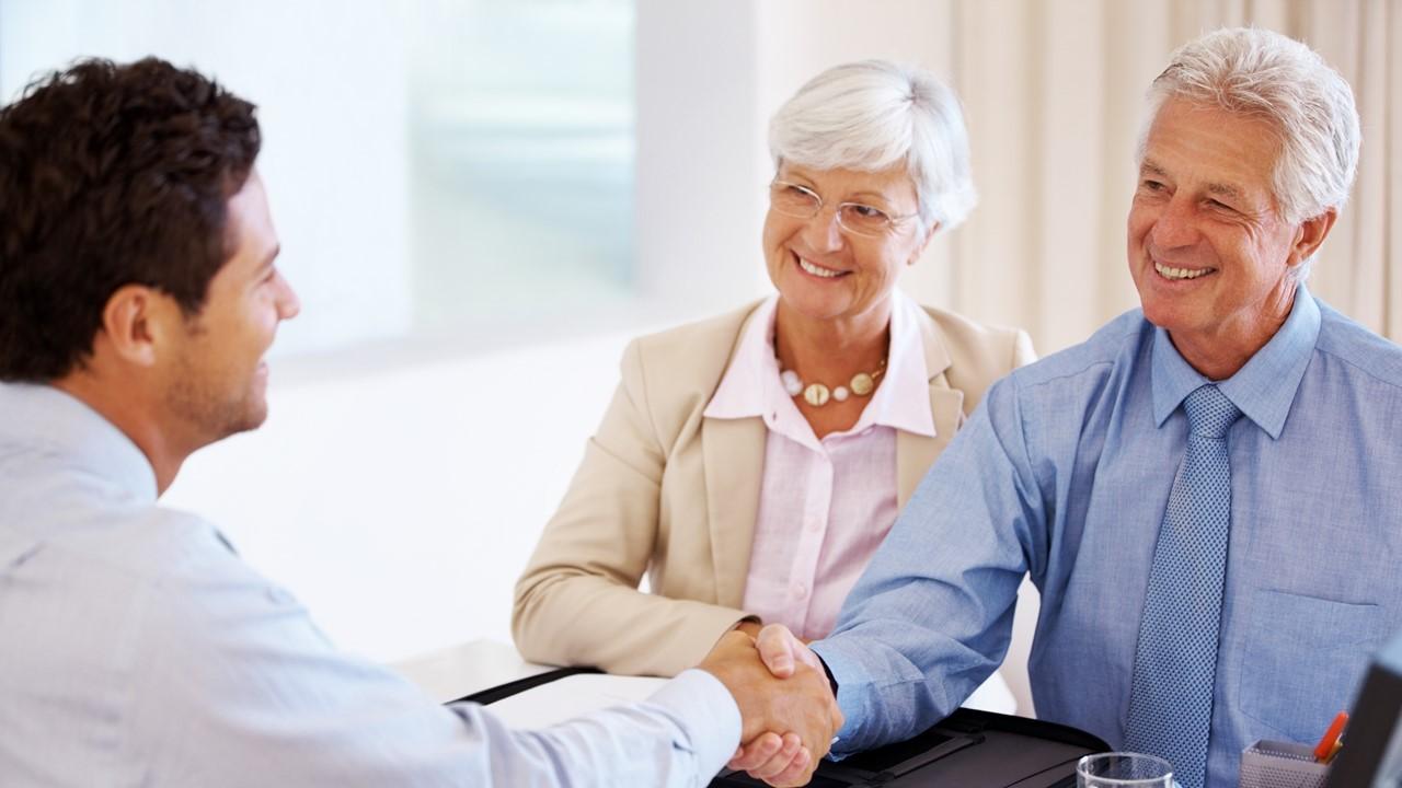 Elderly couple talking to a financial adviser about passive income investments