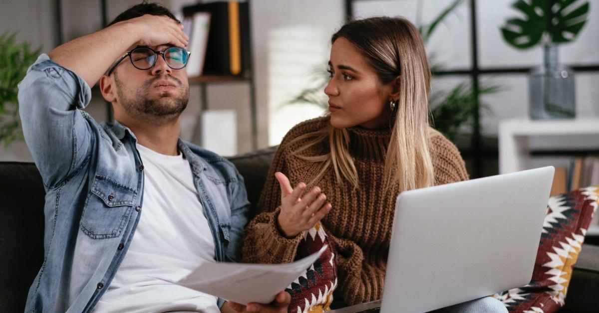 A worried couple who forgot to pay taxes sits in their living room with their computer.