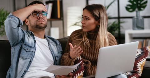 A worried couple who forgot to pay taxes sits in their living room with their computer.