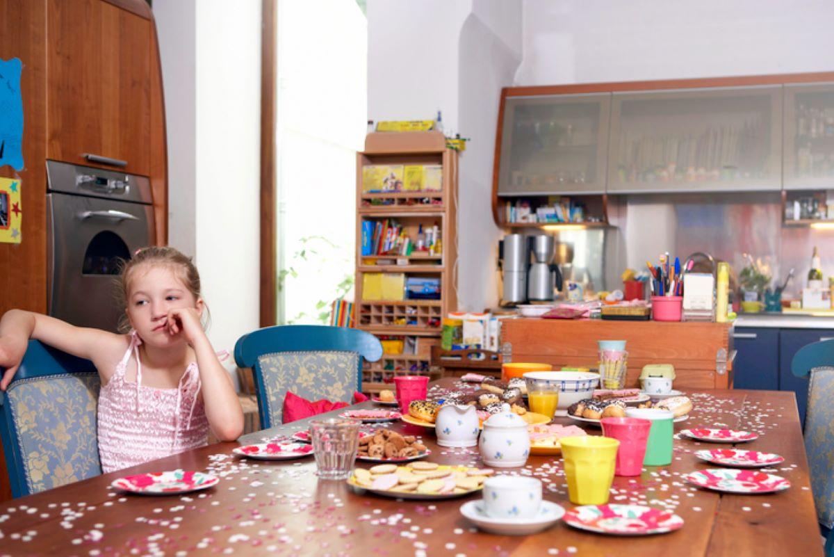 A little girl pouting at the kitchen table