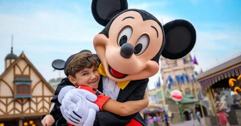 A happy Disney guest embracing Mickey Mouse.