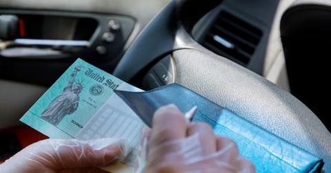 A person holding a government stimulus check in a car