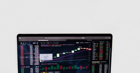 A person fanning cash in front of a computer screen