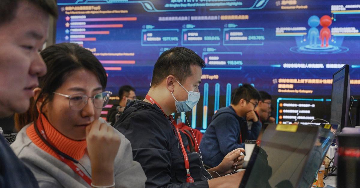 People working at computer terminals in front of a large screen