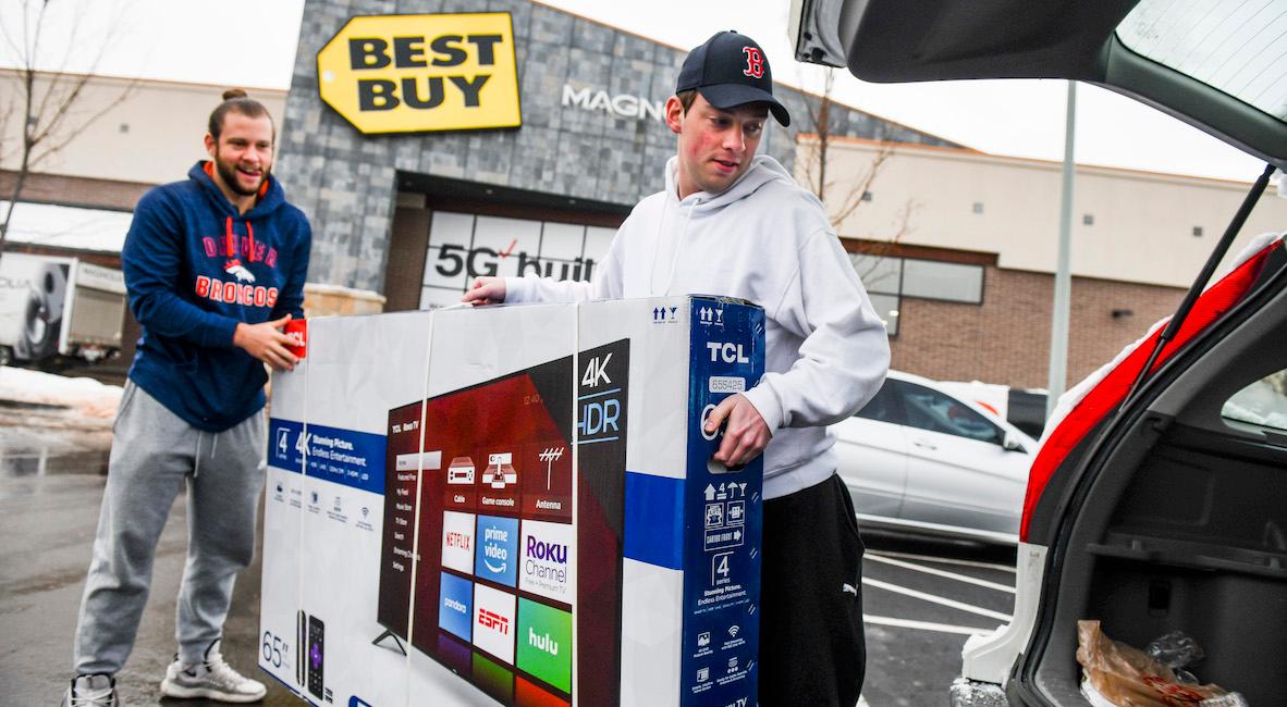 Men loading a Black Friday TV in a car.