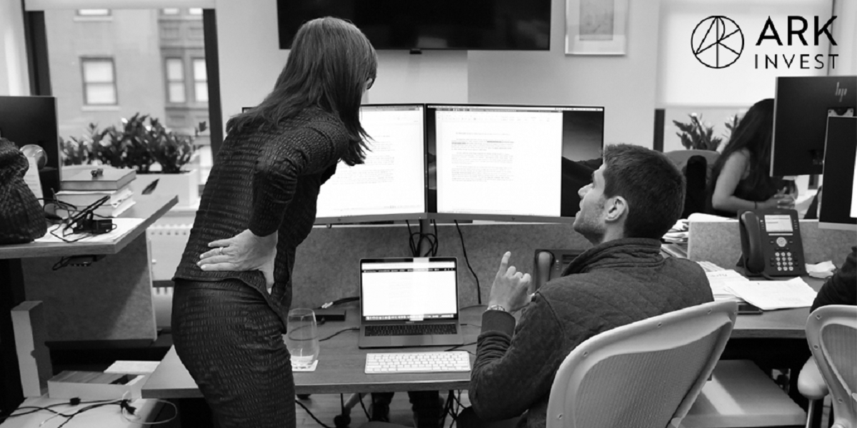 Two people discussing data displayed on computer monitors