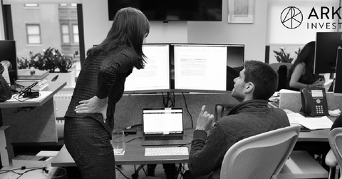 Two people discussing data displayed on computer monitors