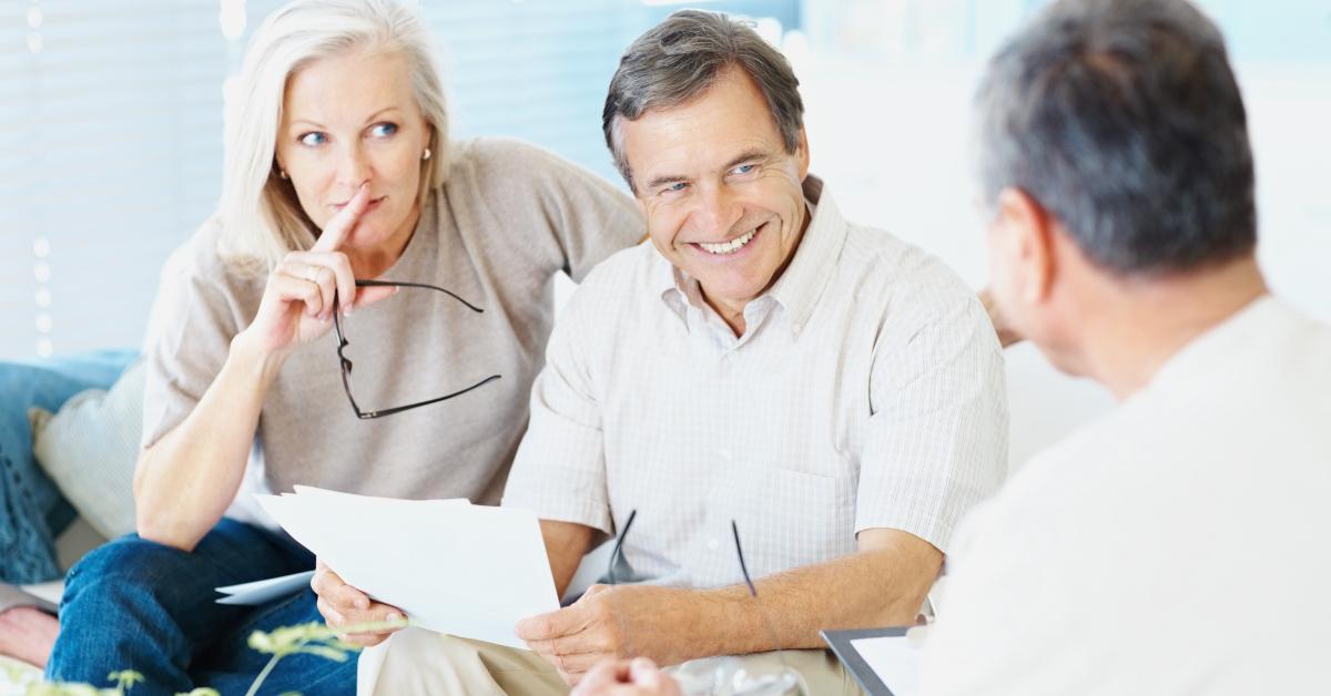 Man holding a piece of paper and talking with two other people