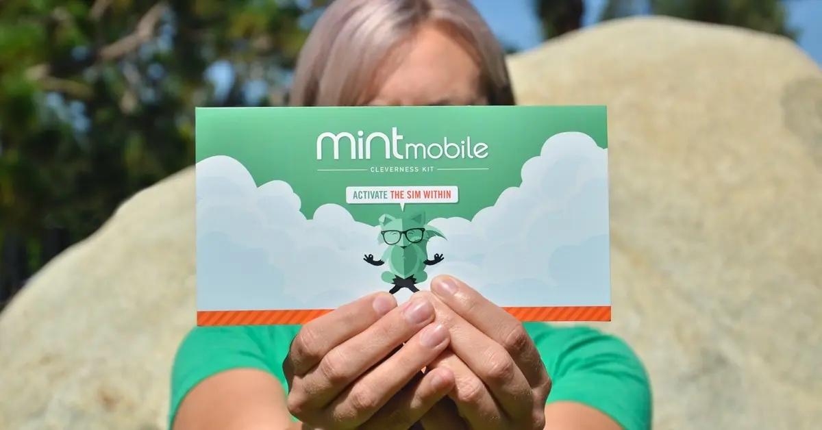 A customer holds a Mint Mobile activation kit.