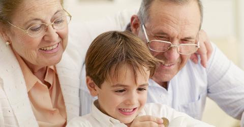 Adults watching child put money in a piggy bank