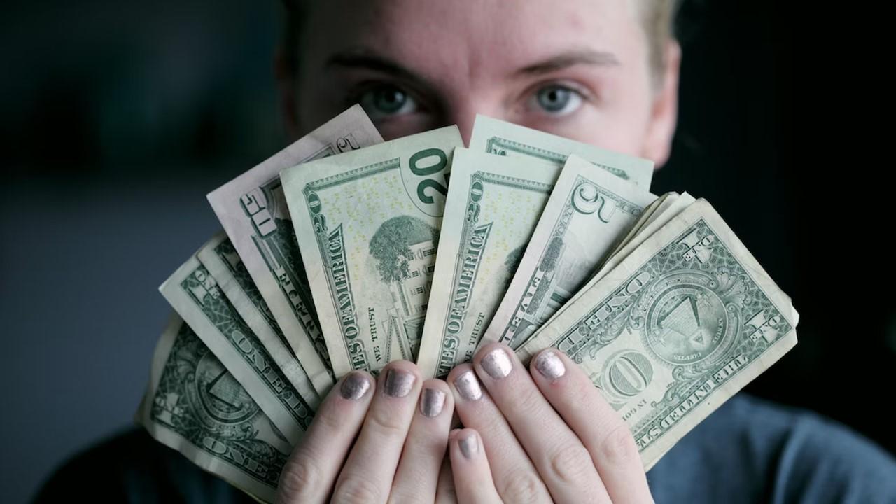 A woman holding cash before depositing it into a tax-free savings account