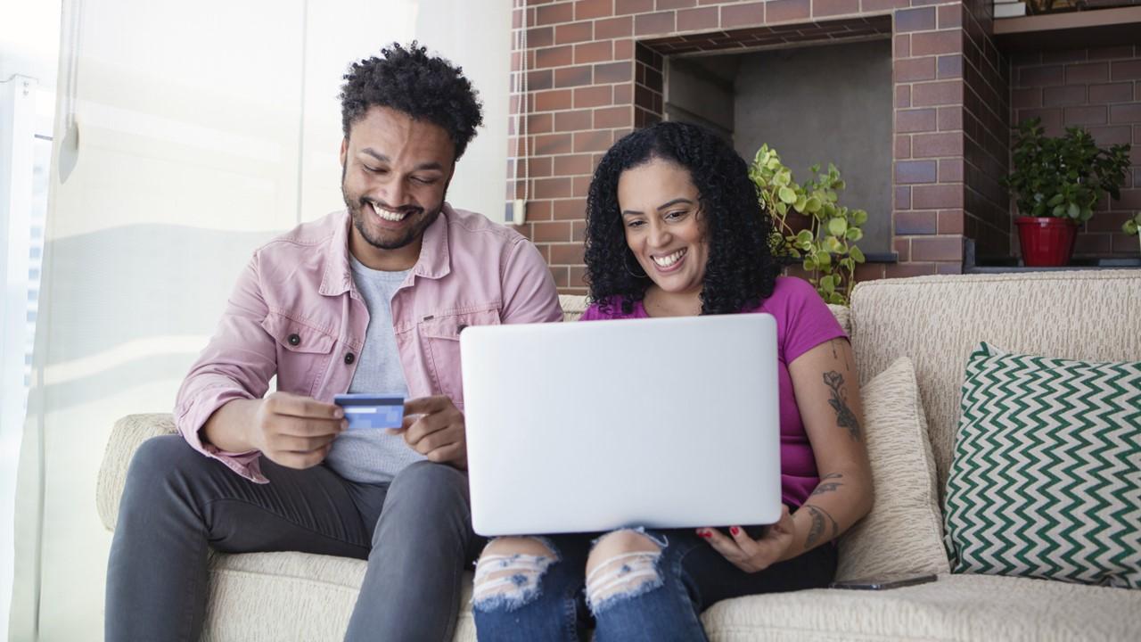 A smiling couple using a Chase credit card to make an online purchase