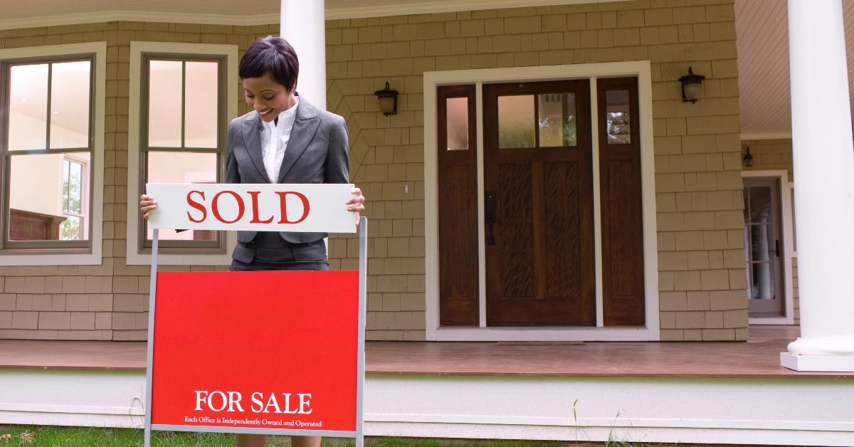 real estate agent putting sold sign on house