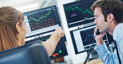A rearview shot of two concerned stockbrokers looking at monitors displaying financial information