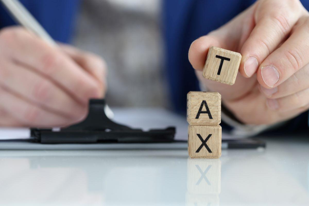 A man filling out tax forms with blocks spelling out 'tax'