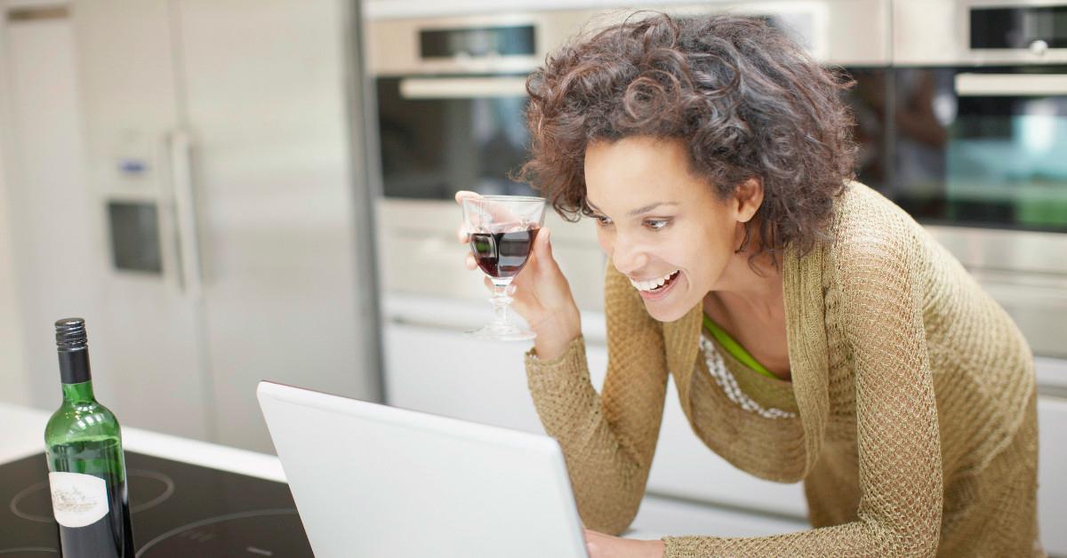 Woman drinking wine and using computer