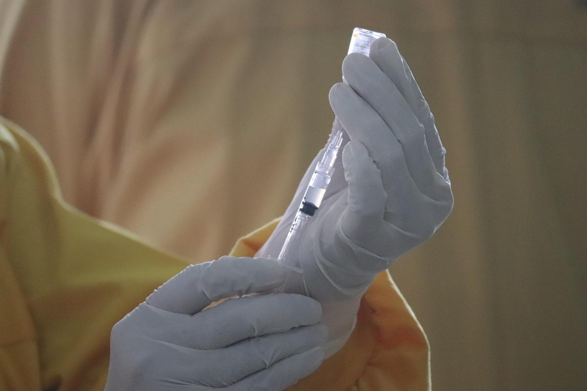 A person prepares a syringe for injection
