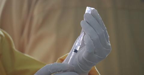 A person prepares a syringe for injection