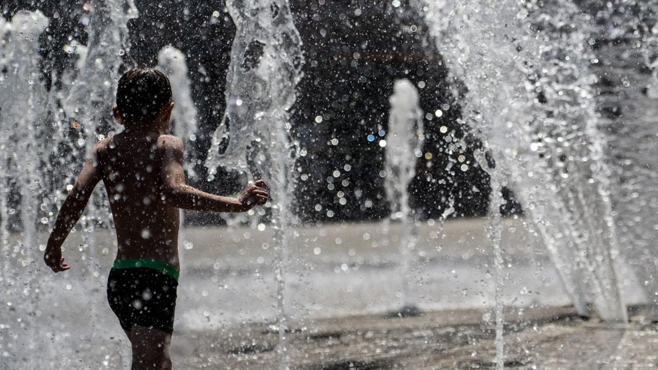 A boy playing in a fountain during a heat wave