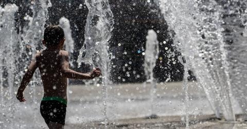 A boy playing in a fountain during a heat wave