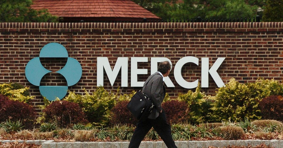 A person walking past the Merck logo on a wall