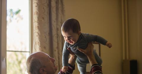 An older adult lifting a baby