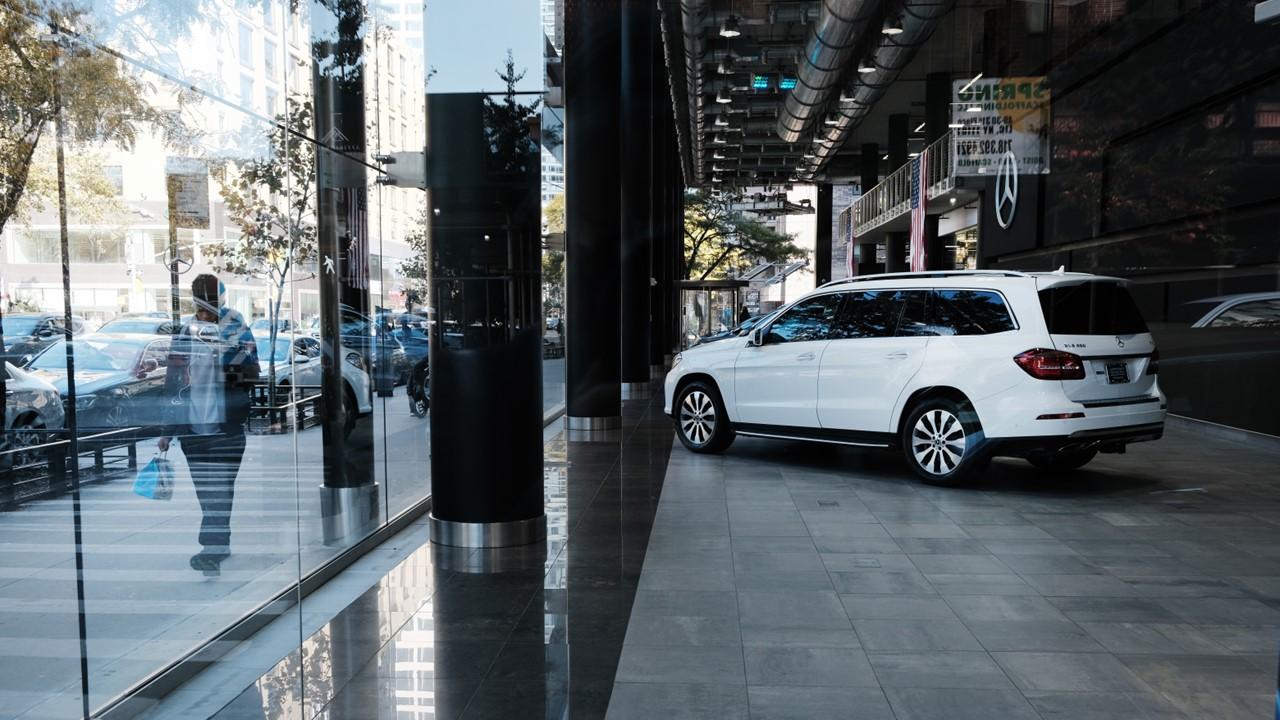 A man walking past a car dealership showroom