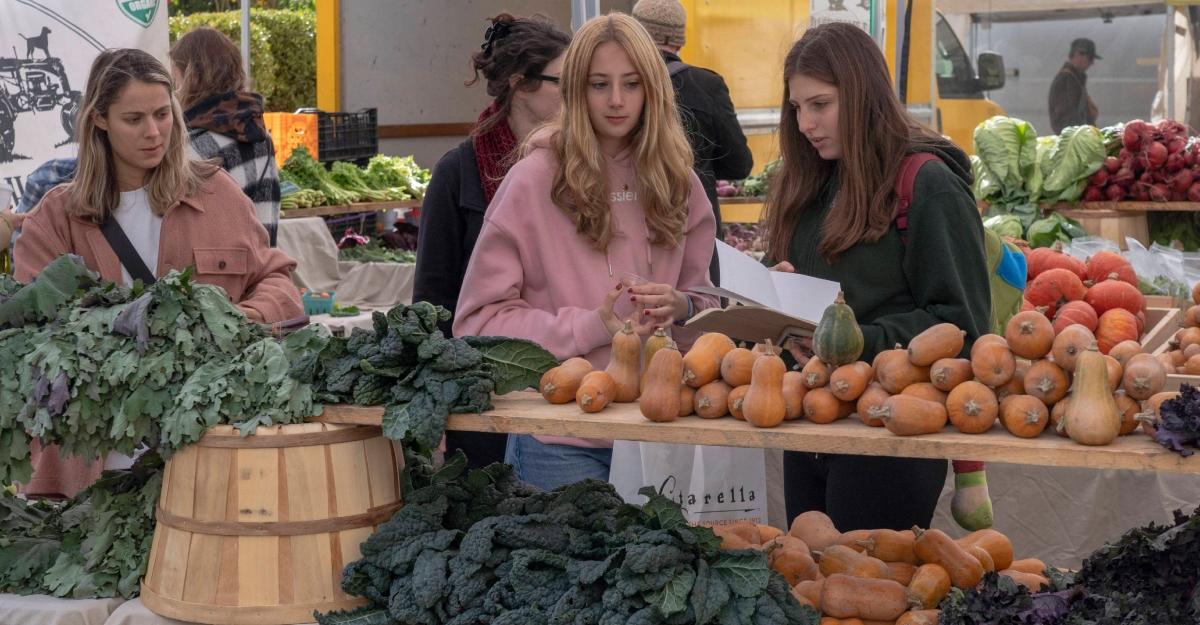 Young women shop for vegetables at a farmers market